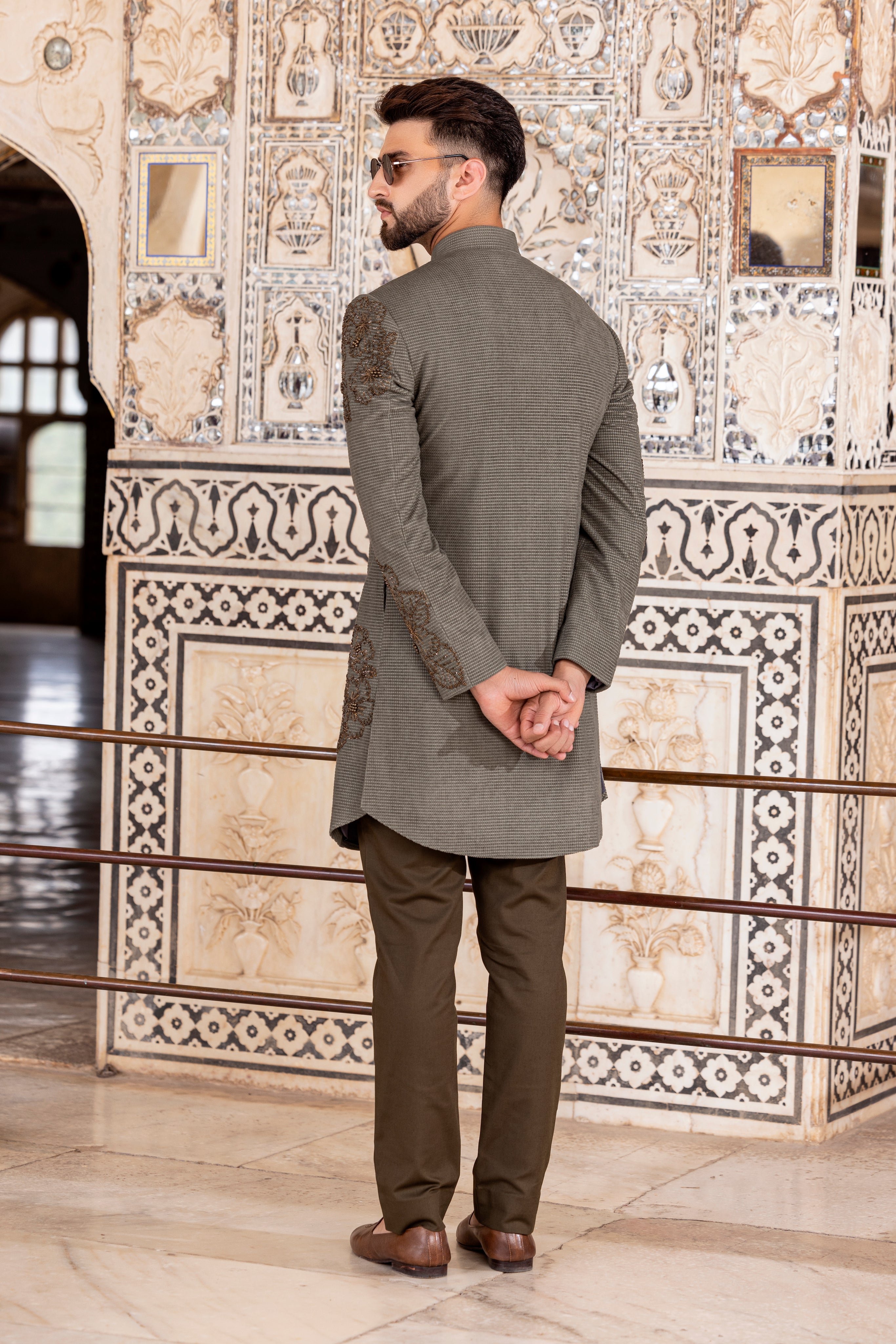 Olive green textured suede indowestern jacket embellished using metal work paired with pants.