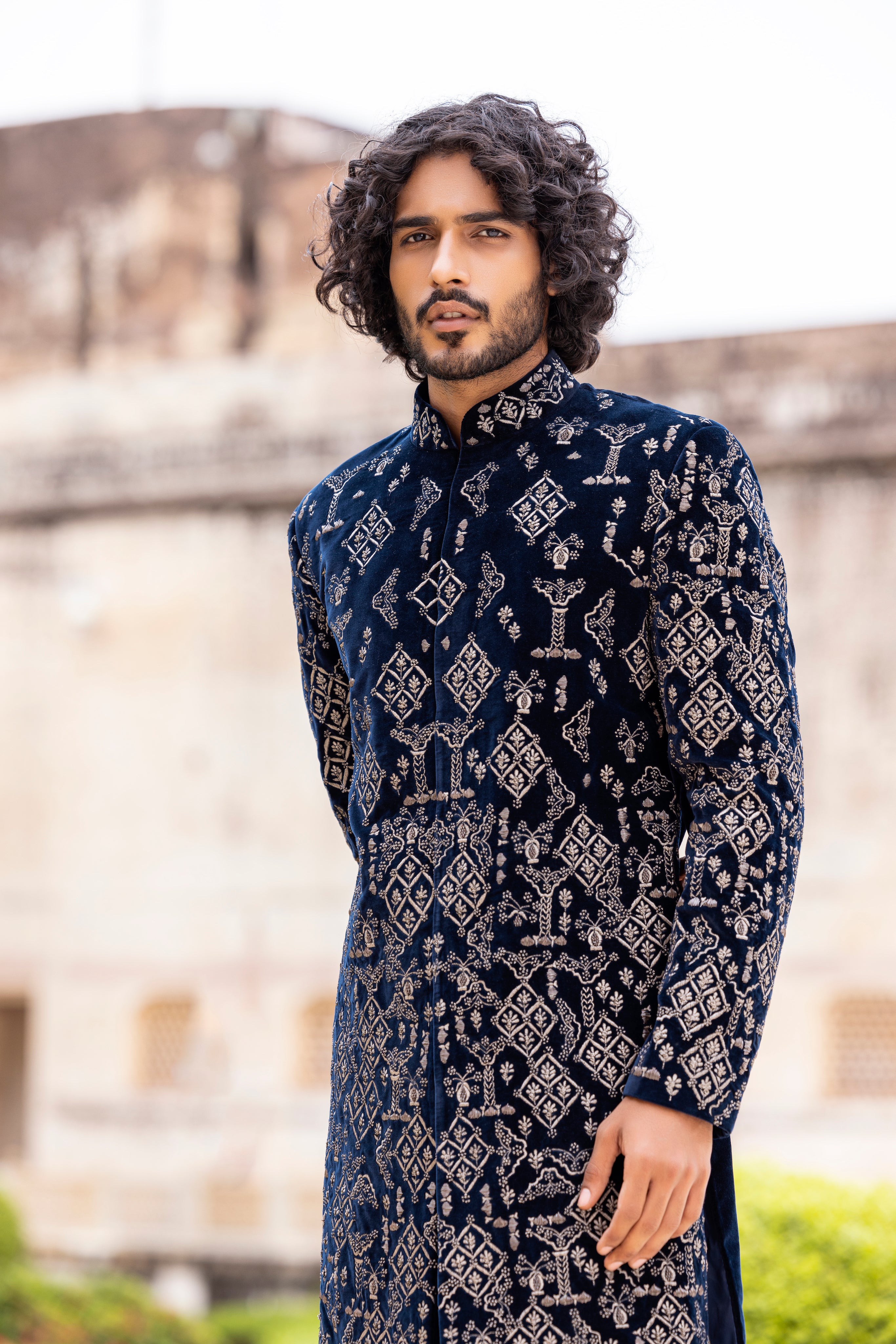 Navy Blue velvet long indowestern jacket highlighted with zari and dabka hand embroidery paired with pants.
