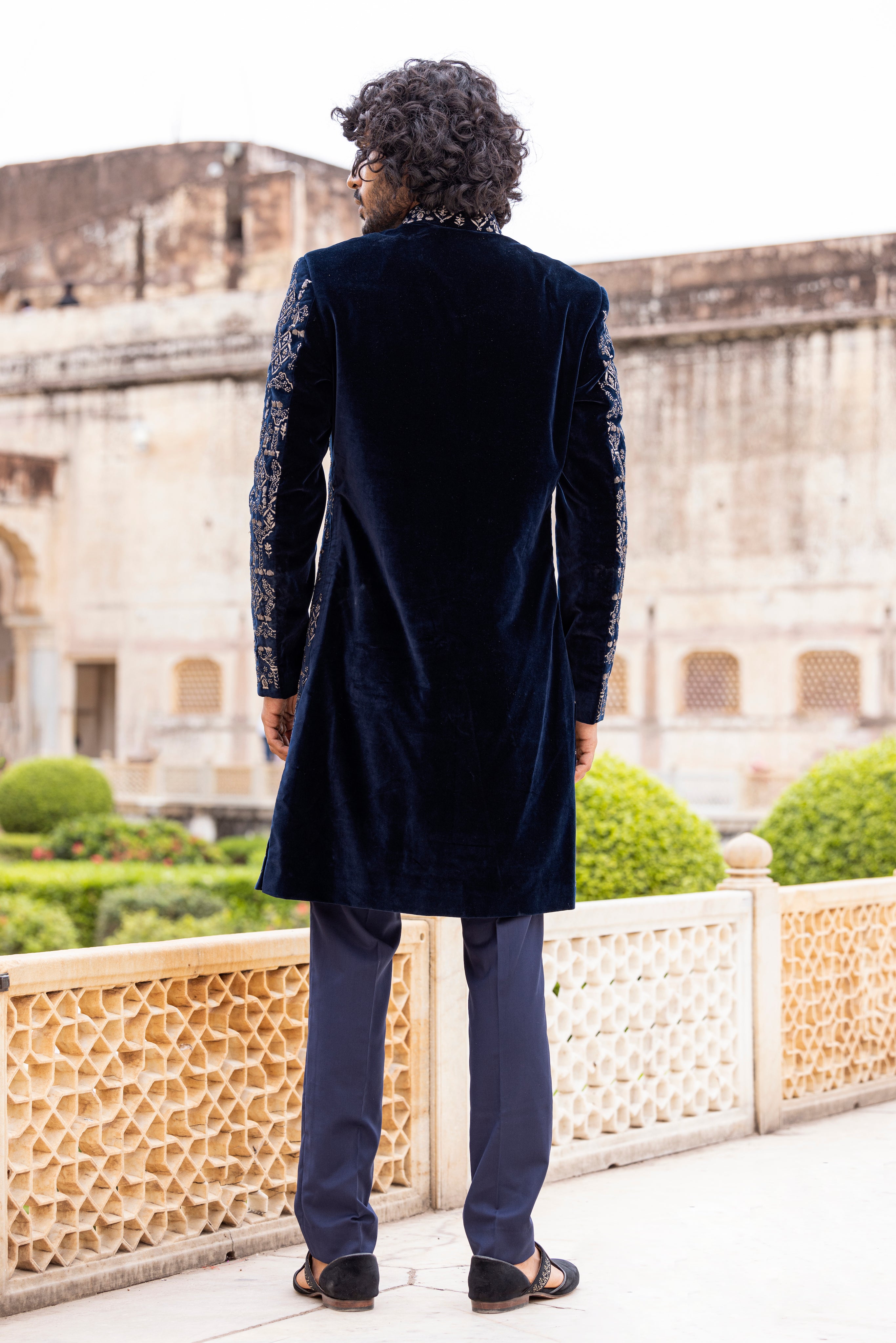 Navy Blue velvet long indowestern jacket highlighted with zari and dabka hand embroidery paired with pants.