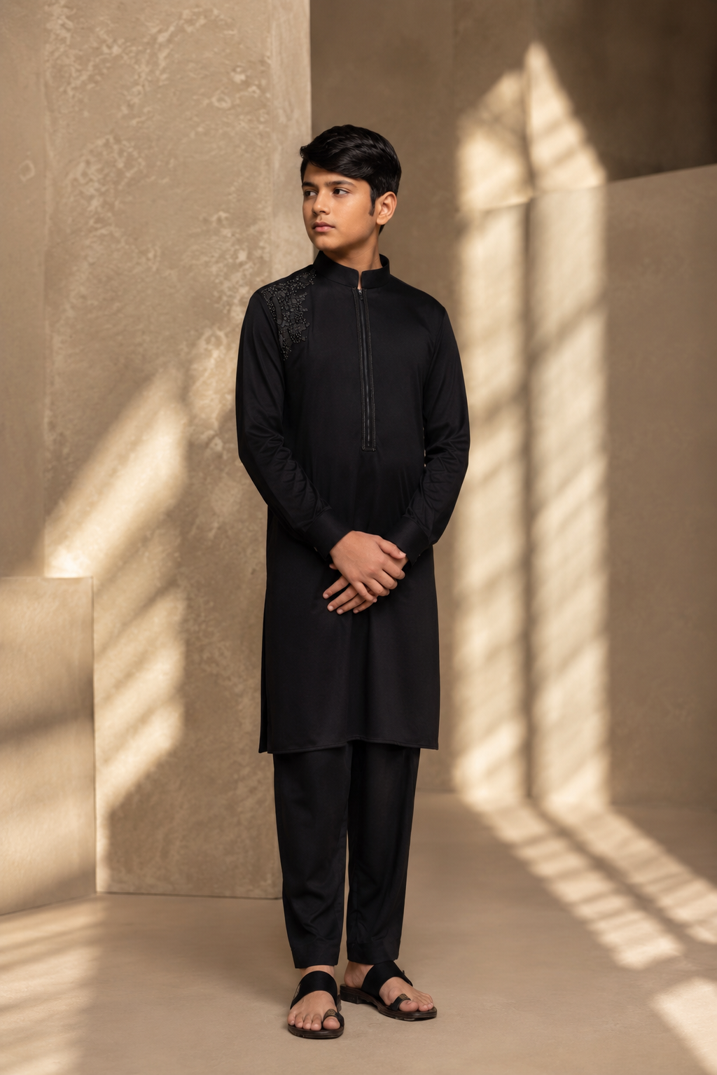 Featuring black knit kurta embellished with antique metal components on one shoulder and zipper detailing paired with aligarhi pants